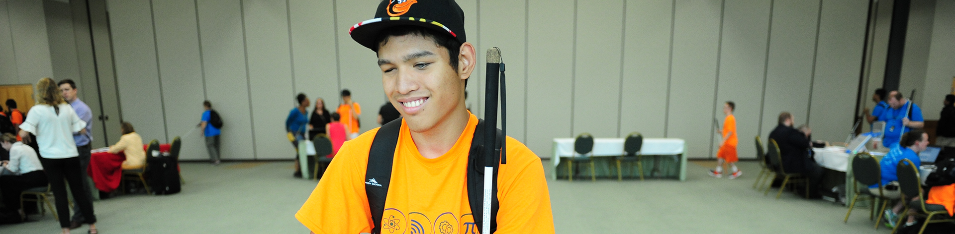 A blind young man smiles as he explores a student expo.